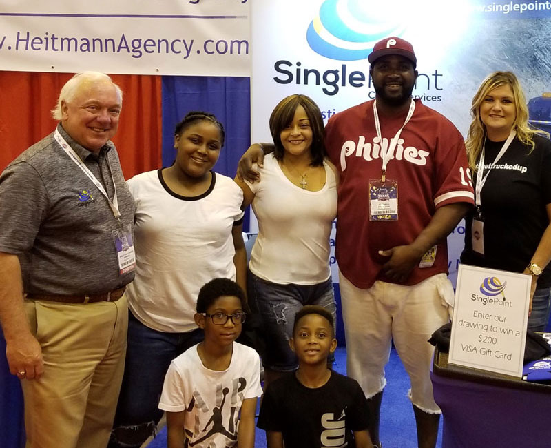 CEO of Single Point Carrier Services Next To Trucker and Family At The Texas Trucking Show